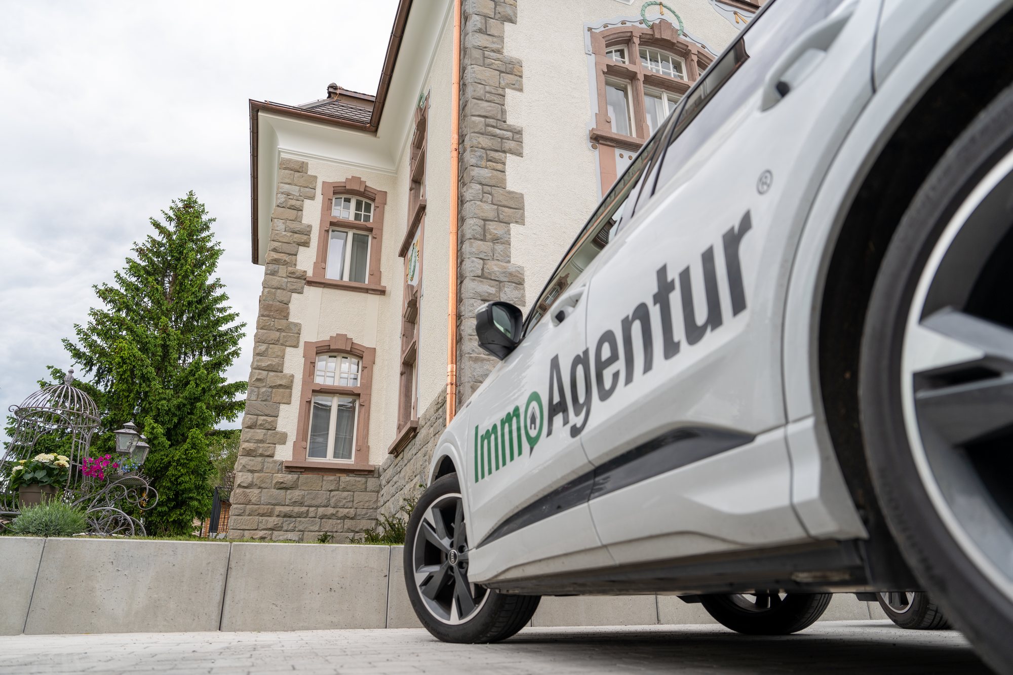 Firmenwagen mit ImmoAgentur-Schriftzug vor einer historischen Villa